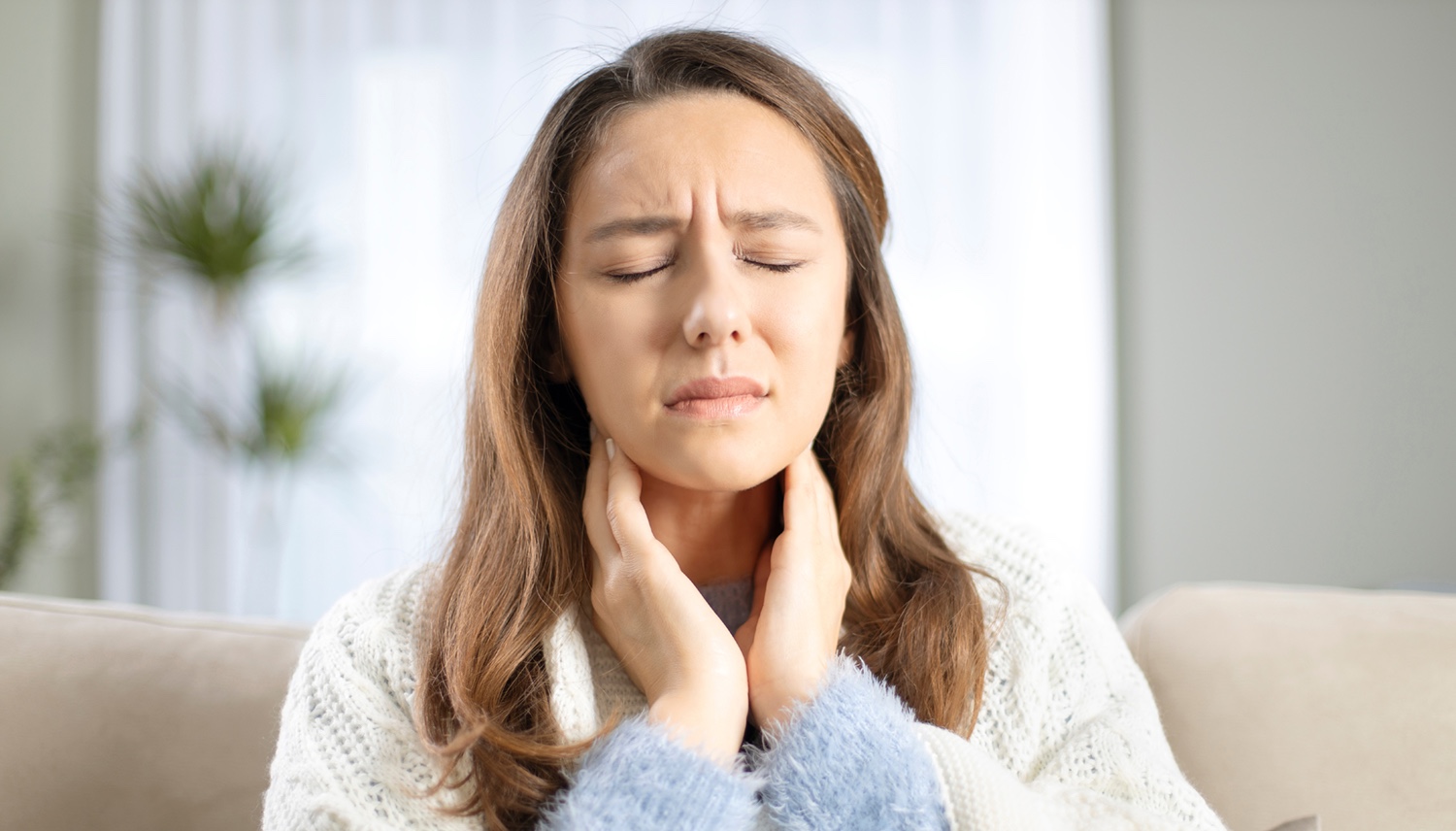 Young woman touching painful neck